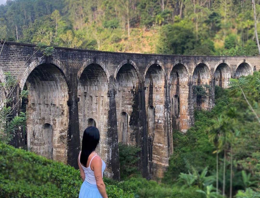 Wide angle view of the Nine Arches Bridge surrounded by lush greenery