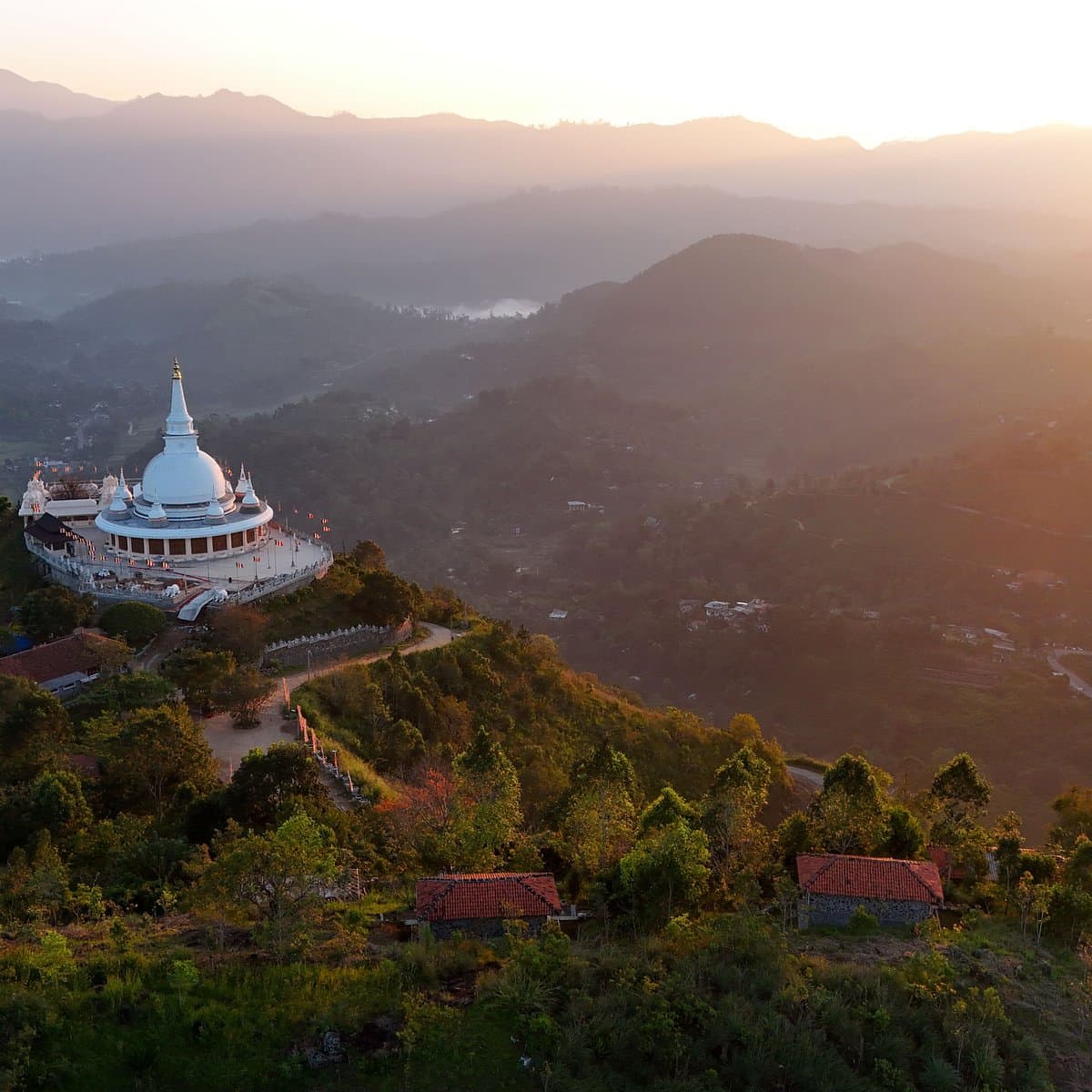 The white stupa of Mahamevnawa Buddhist Monastery above the hills near Ella at dusk